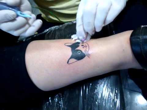 Artista haciendo el tatuaje de un gatito en